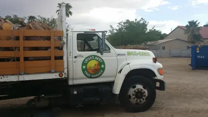 Vegas Best Tree Service flatbed truck loaded with cut branches beside a dumpster