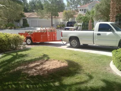 Pickup truck and orange dump trailer in a Las Vegas driveway after a yard cleanup