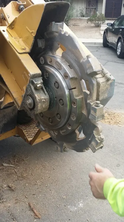 Close-up of a stump grinder's toothed cutting wheel on a Las Vegas driveway