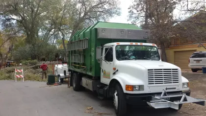 Loaded Vegas Best Tree Service chipper truck on a tree-lined Las Vegas street during a cleanup
